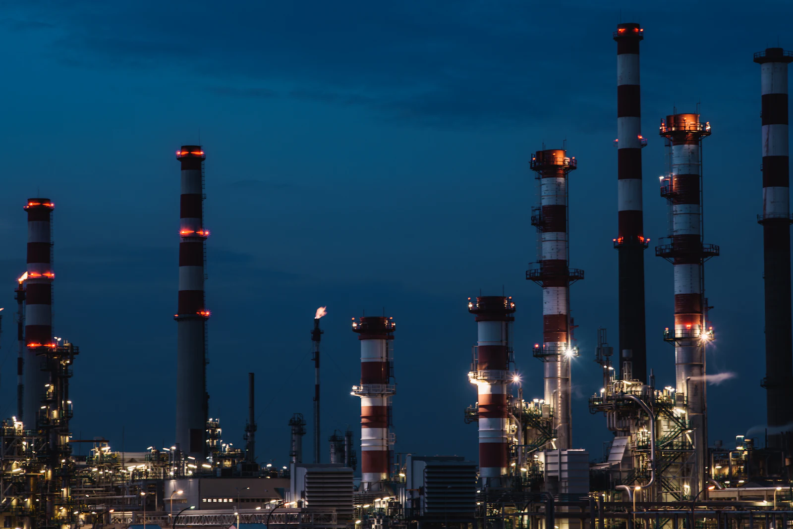 Refinery stacks and process columns lit at dusk